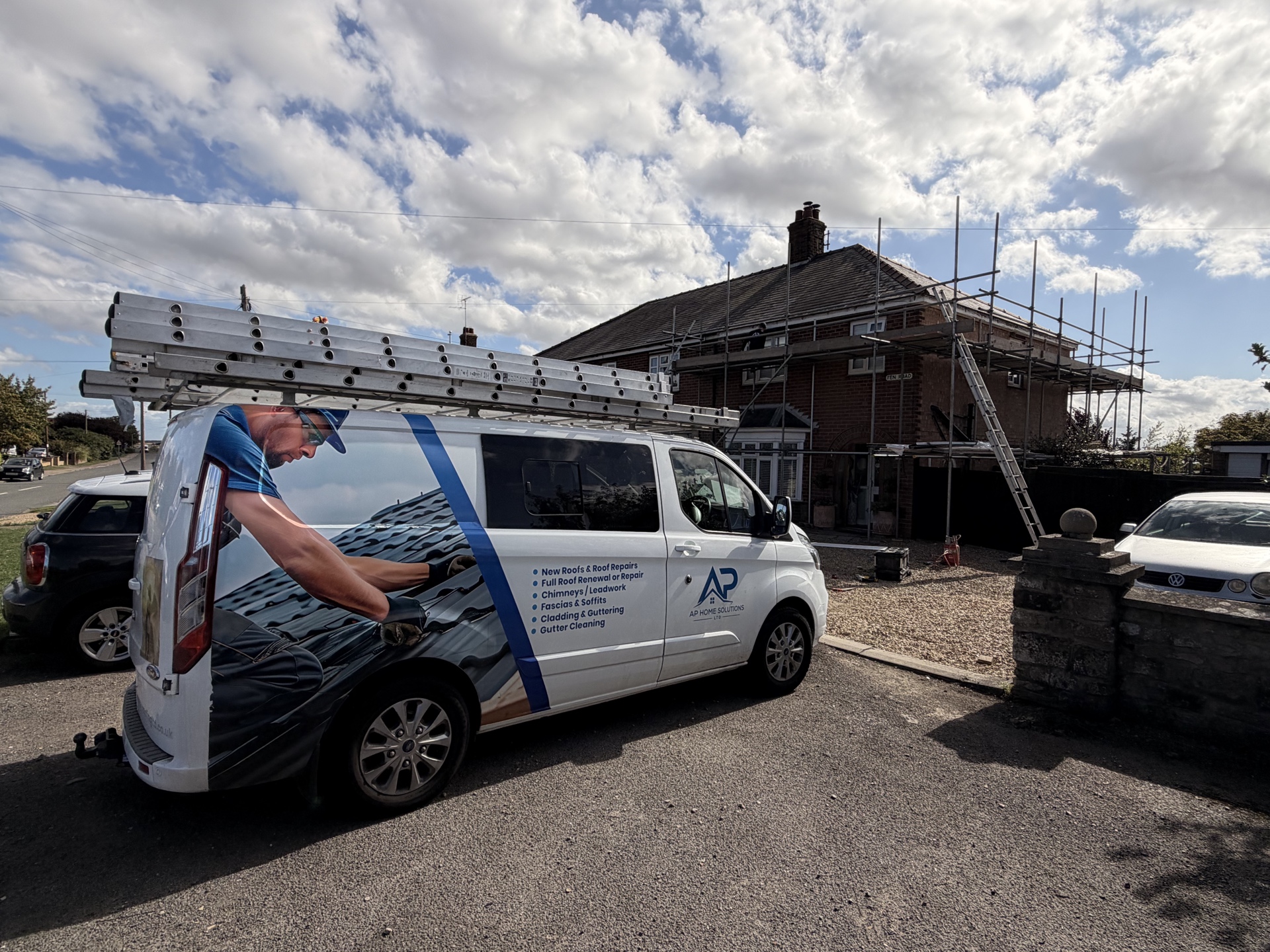 Roofing team and branded van beside scaffold