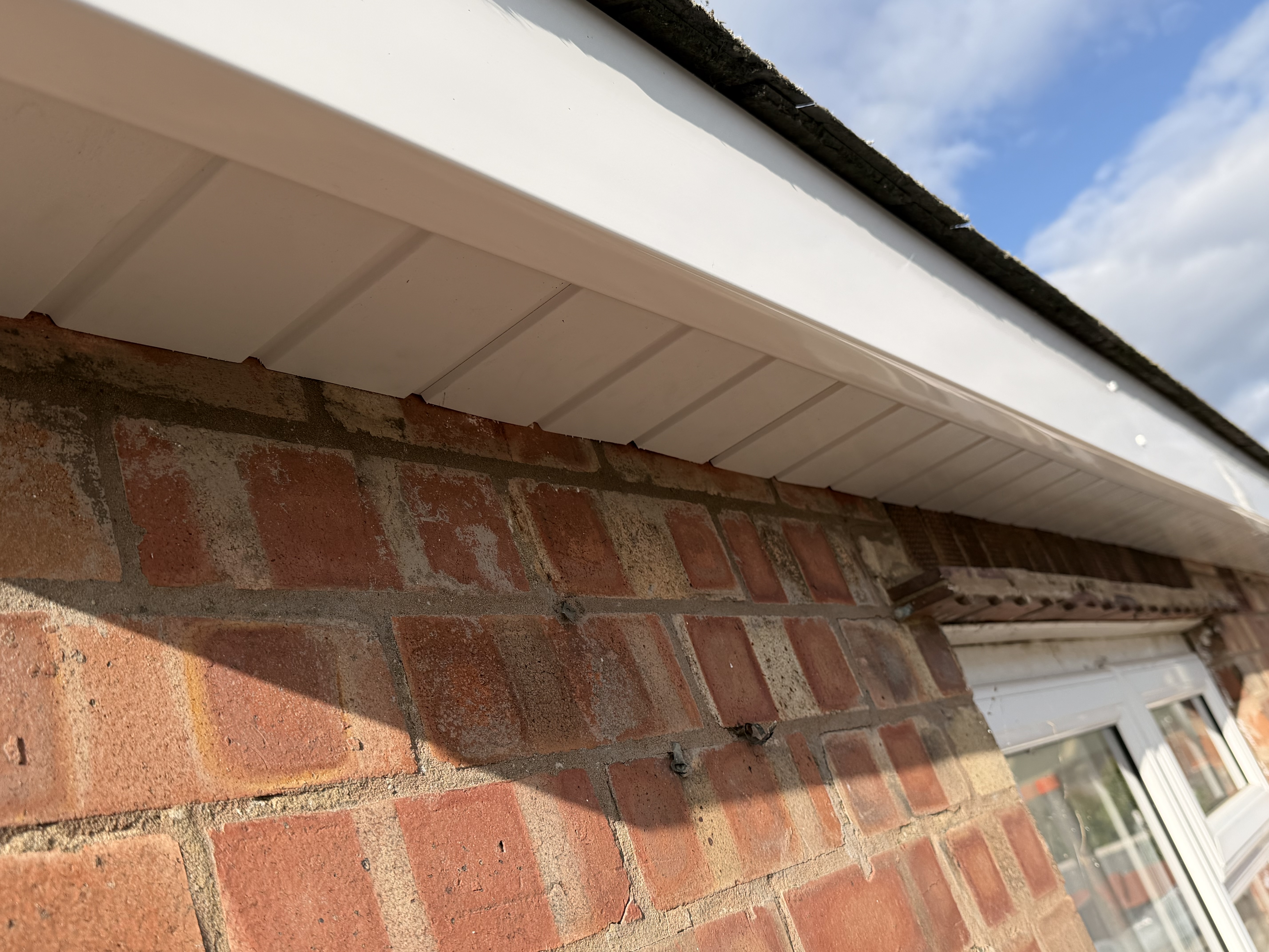 White roof edge and soffit detail above brickwork