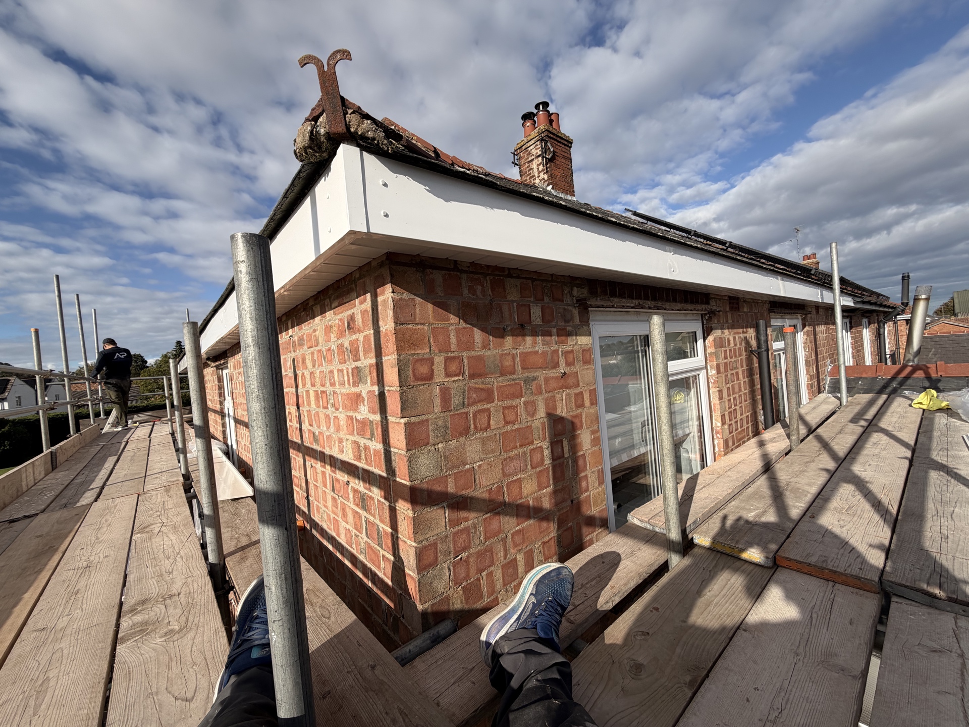 Scaffolded side elevation with roofer working at the roof edge