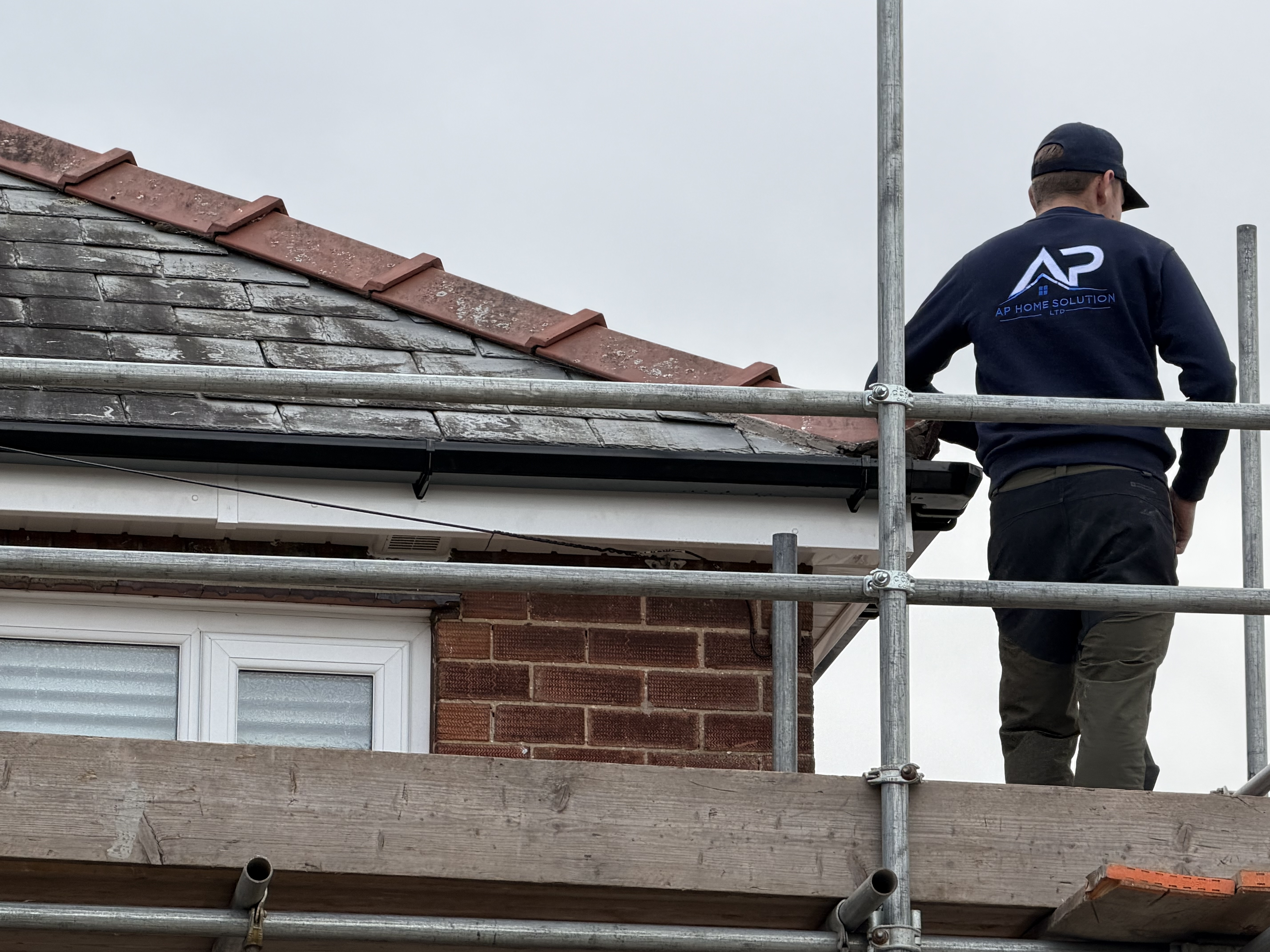 Roofer working from scaffold beside the roofline