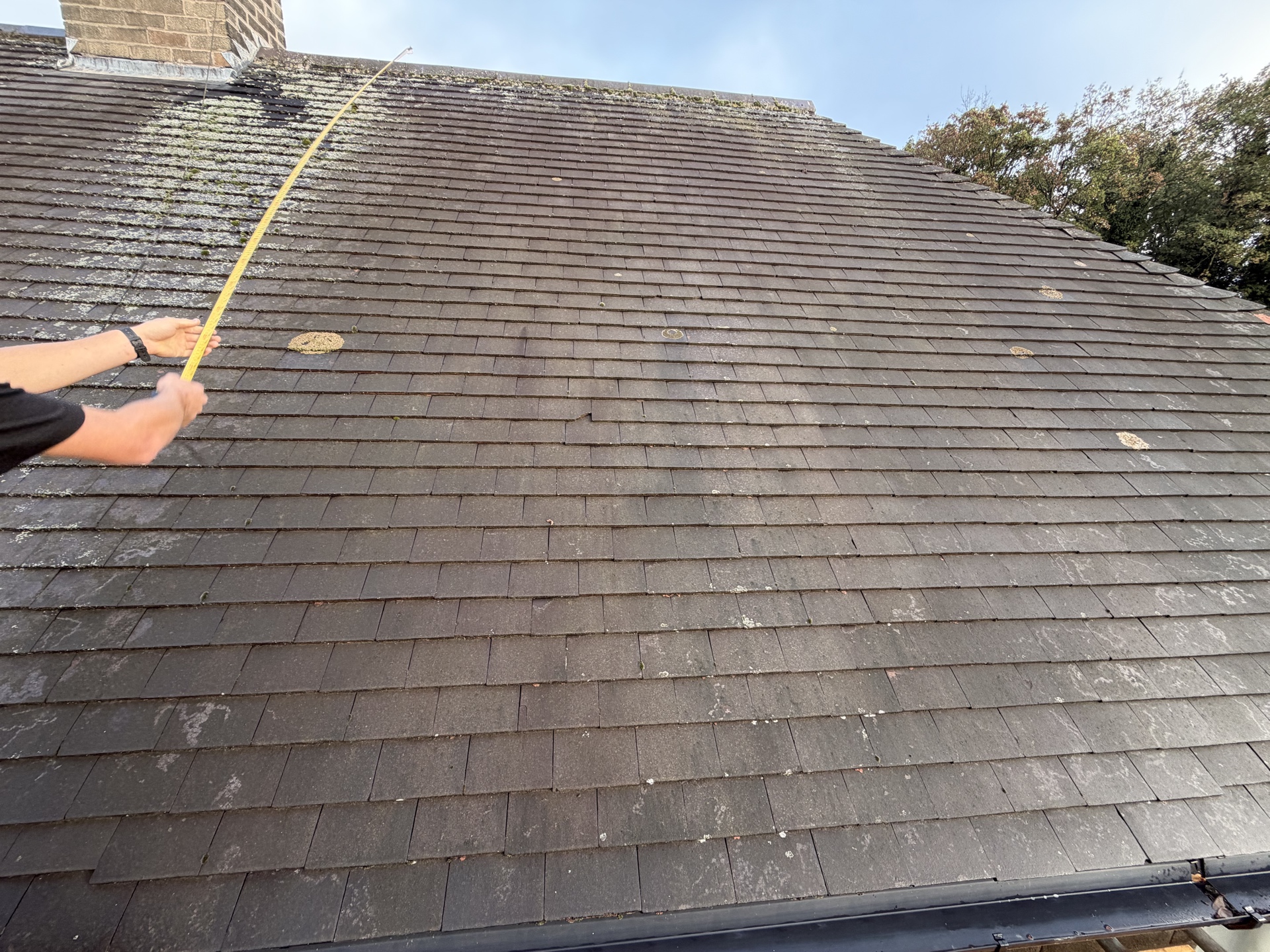 Close inspection of weathered roof tiles beside a gutter
