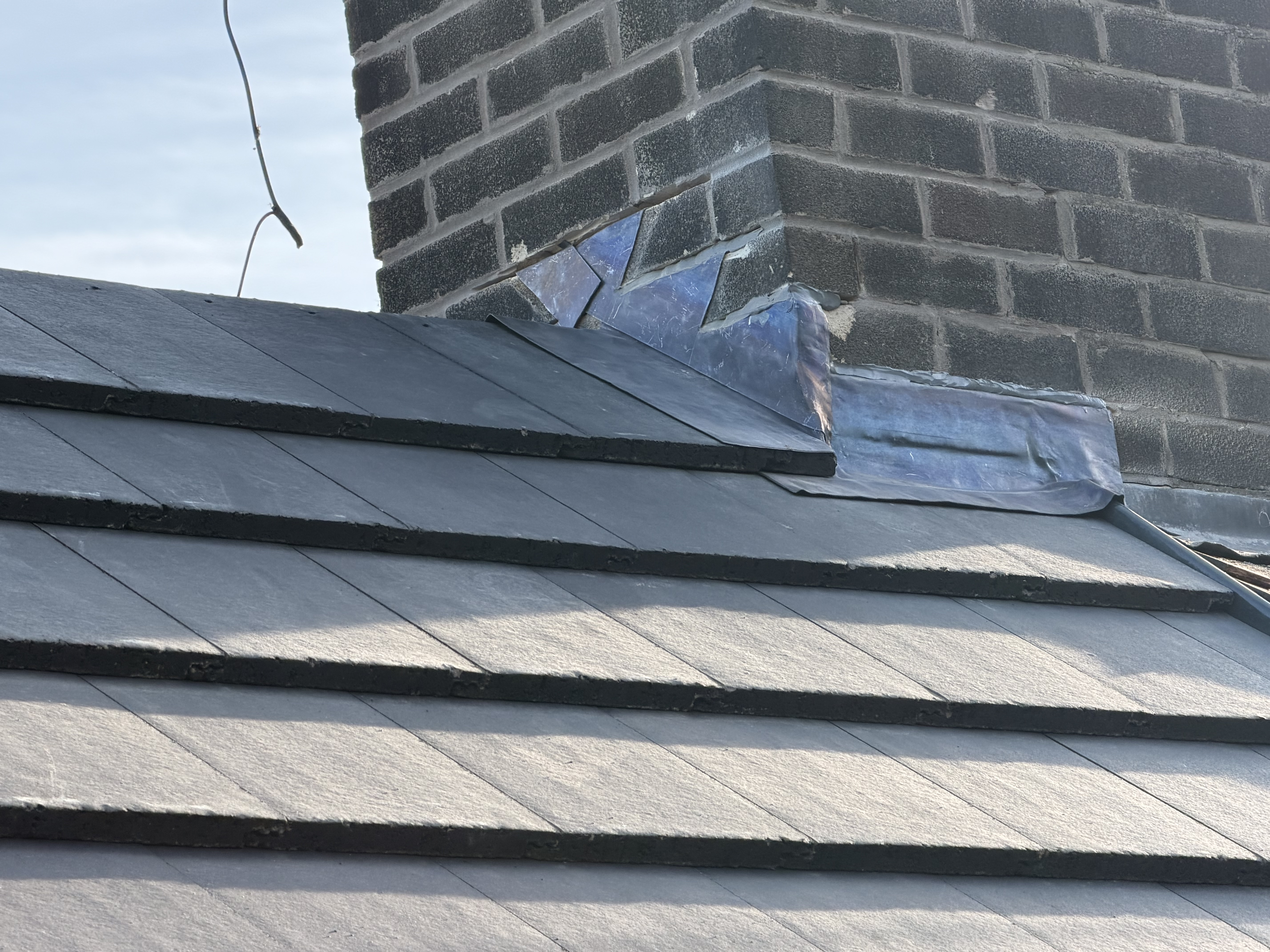 Completed roof tiles and lead flashing around a brick chimney