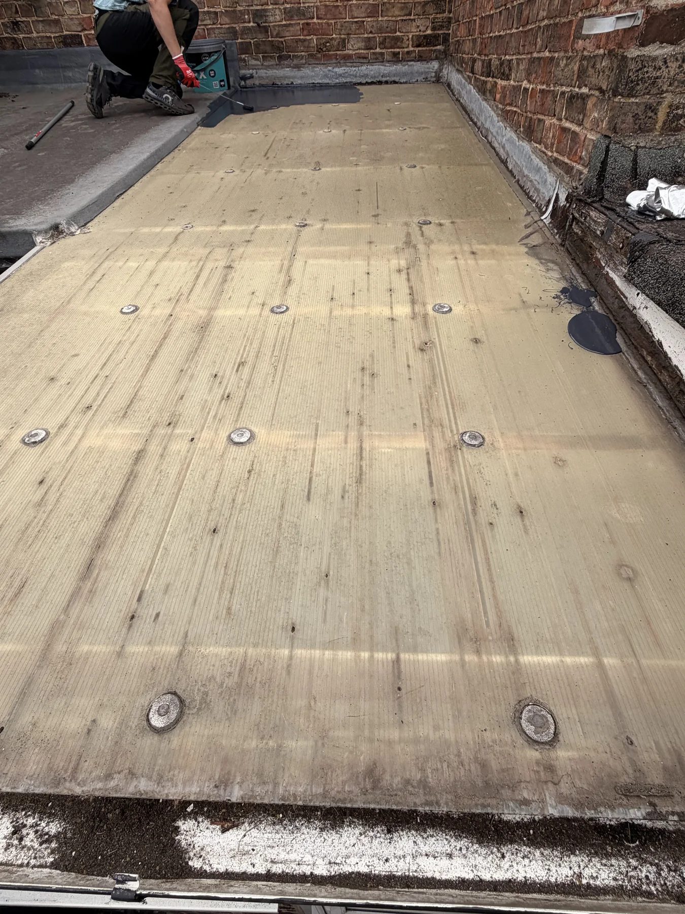Flat-roof work in progress with rigid boards secured across the deck